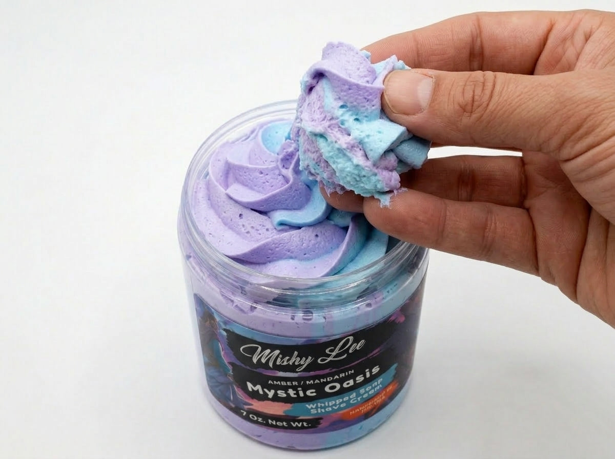 Hand holding a scoop of purple-and-blue whipped shave cream foam above jar.