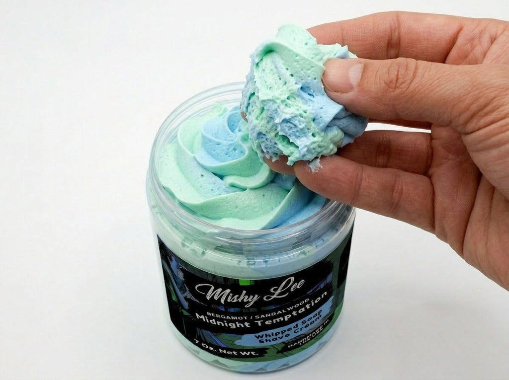 Hand scooping mint and blue whipped shave cream from a Mishy Lee jar