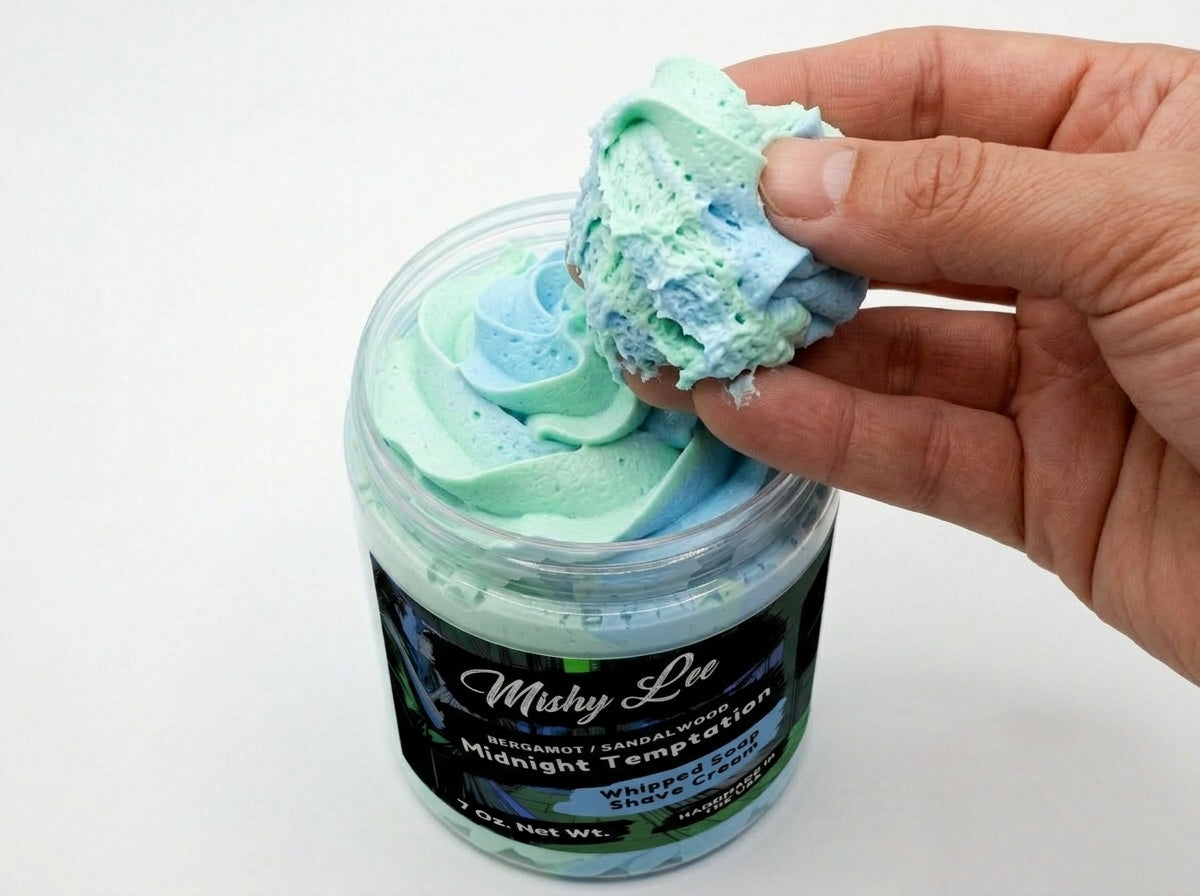 Hand scooping mint and blue whipped shave cream from a Mishy Lee jar