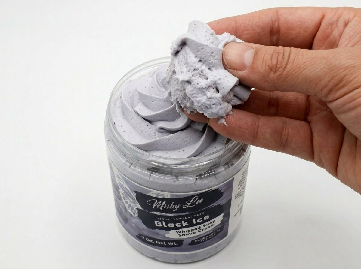Hand holding light purple whipped soap from a black ice shave cream jar