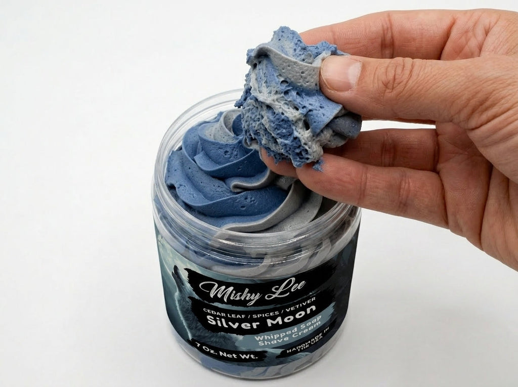 Hand holding a scoop of blue whipped soap from a Mushy Lee Silver Moon jar