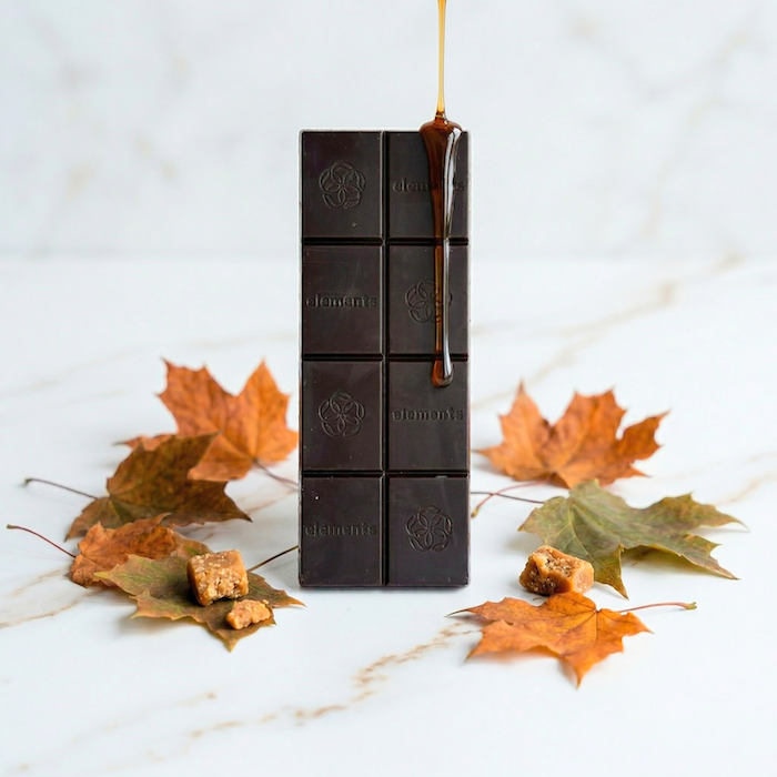 Maple toffee chocolate bar pieces on a white surface with scattered autumn leaves