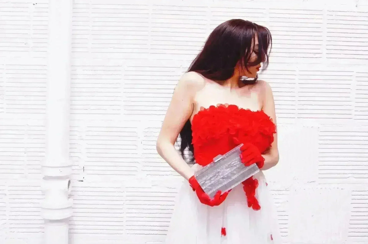 Silver stripe box clutch with metallic clasp, held in hand