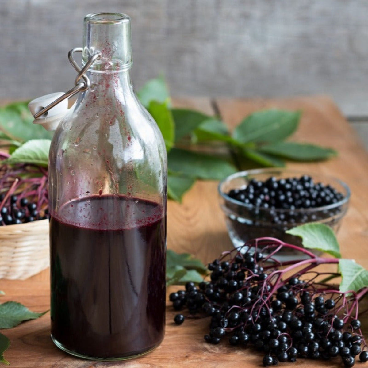 Elderberry syrup in glass bottle with elderberries on wooden surface