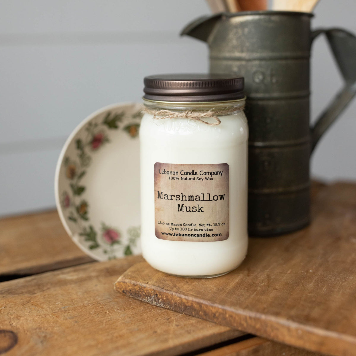 Marshmallow Musk soy candle in clear jar with brown lid and label on wood