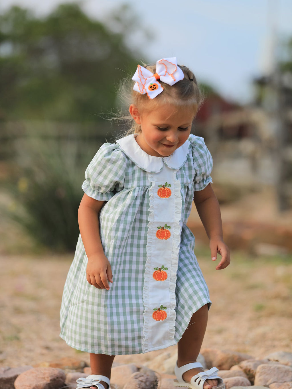 Green gingham girls dress with white ruffle front and vertical pumpkin applique, puff sleeves