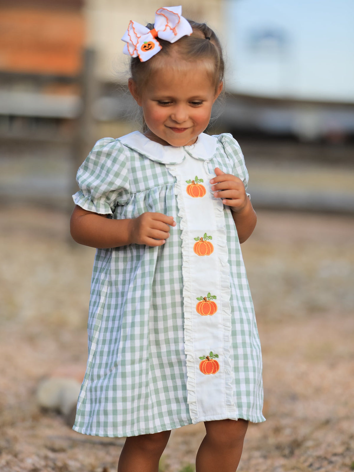 Green gingham girls dress with white ruffle bib and orange pumpkin appliques