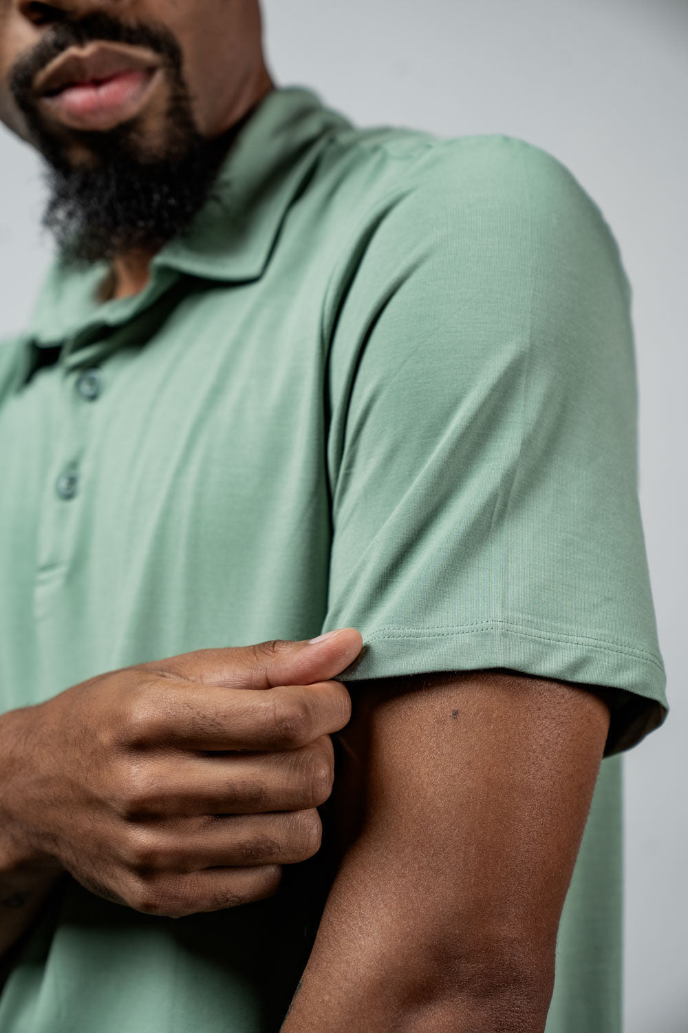 Olive polo shirt sleeve close-up with seam and button placket