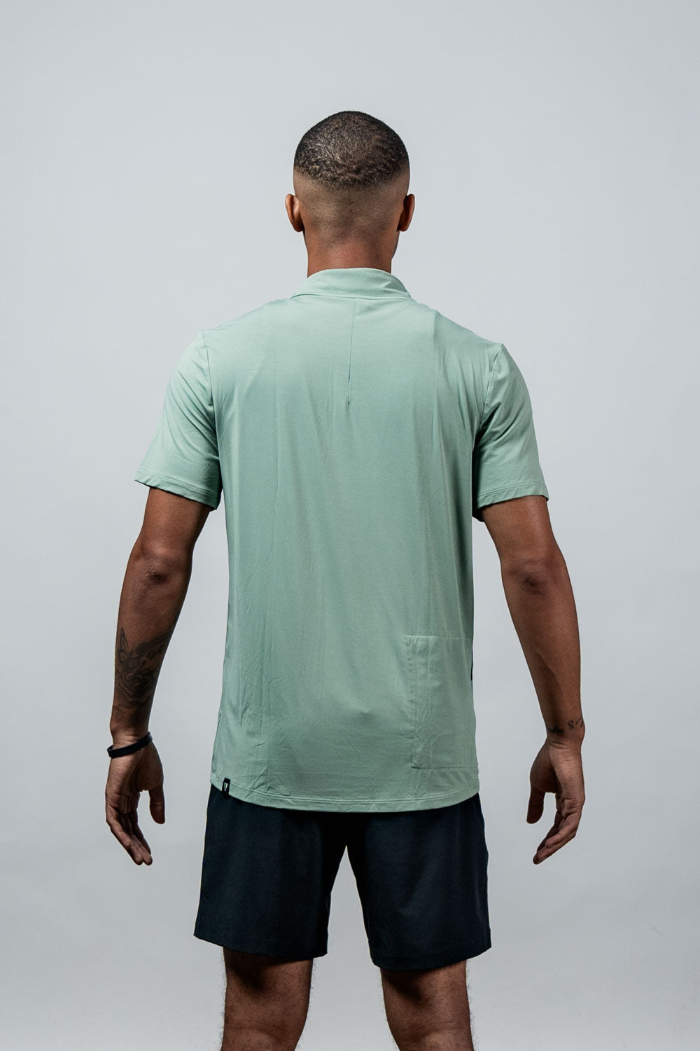 Men's low-light olive polo shirt, back view with short sleeves and collar.
