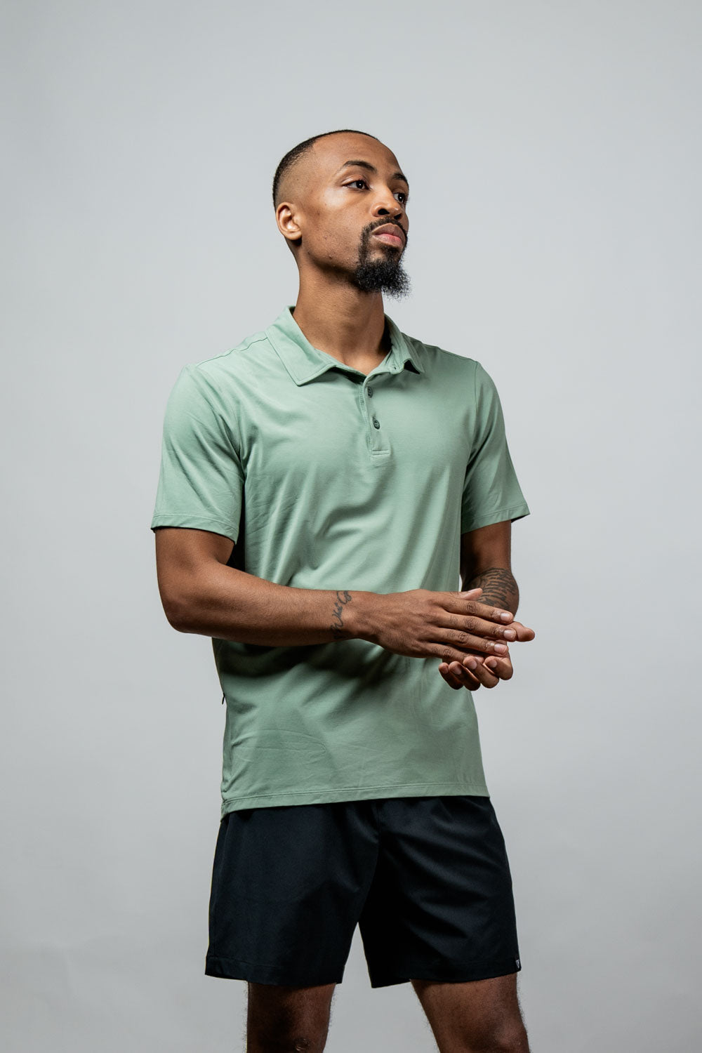 Men's low-light olive polo shirt on model, short sleeves and three-button placket.