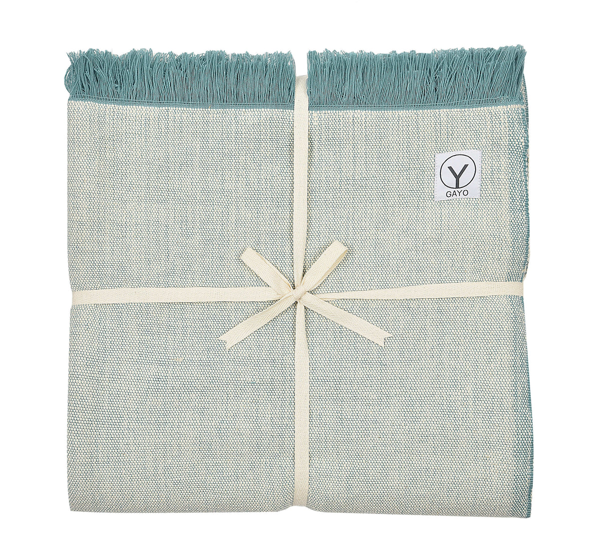 Light sage yoga blanket with teal fringe, folded bundle with logo patch and ribbon bow.