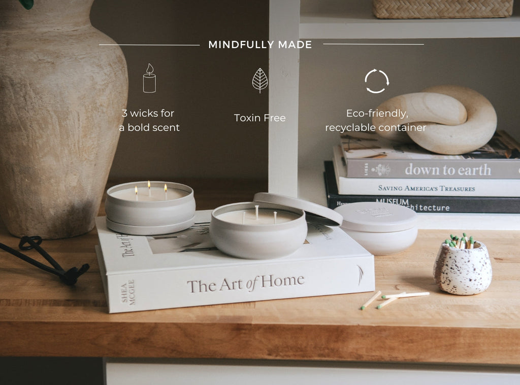 Three white candles in matching jars on a wooden tray, varying heights