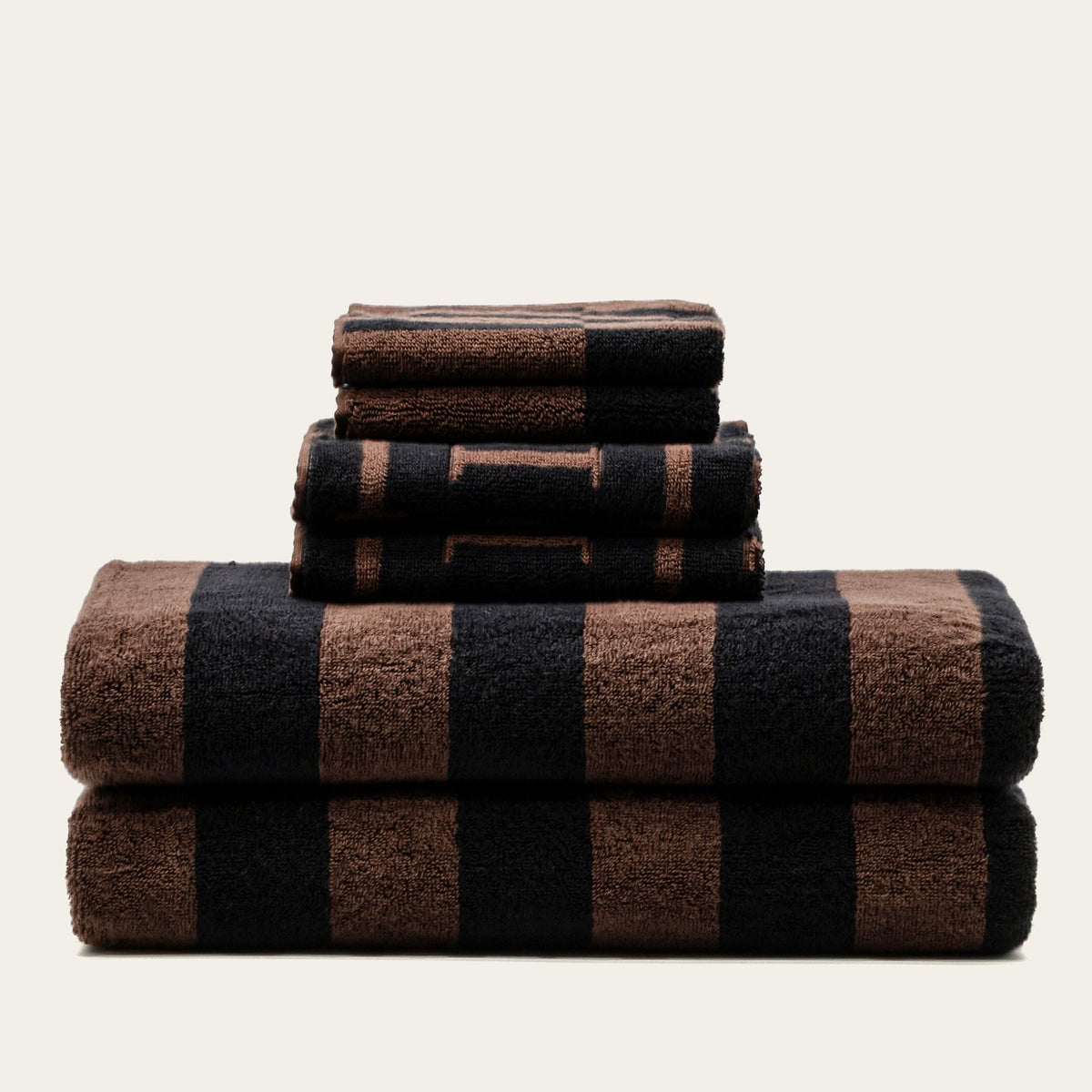 Stack of striped cotton bath towels in tobacco brown and black, neatly folded
