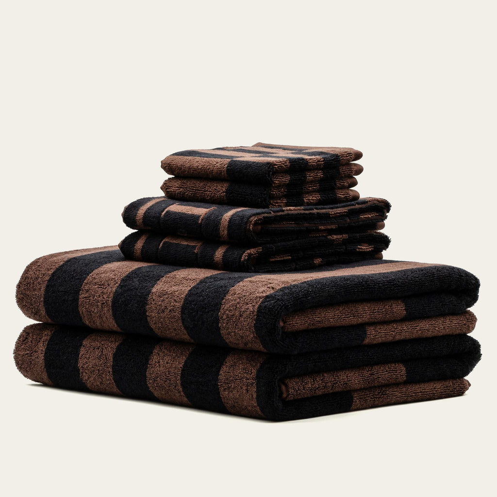 Stack of striped cotton towels in tobacco brown and black with rolled edges