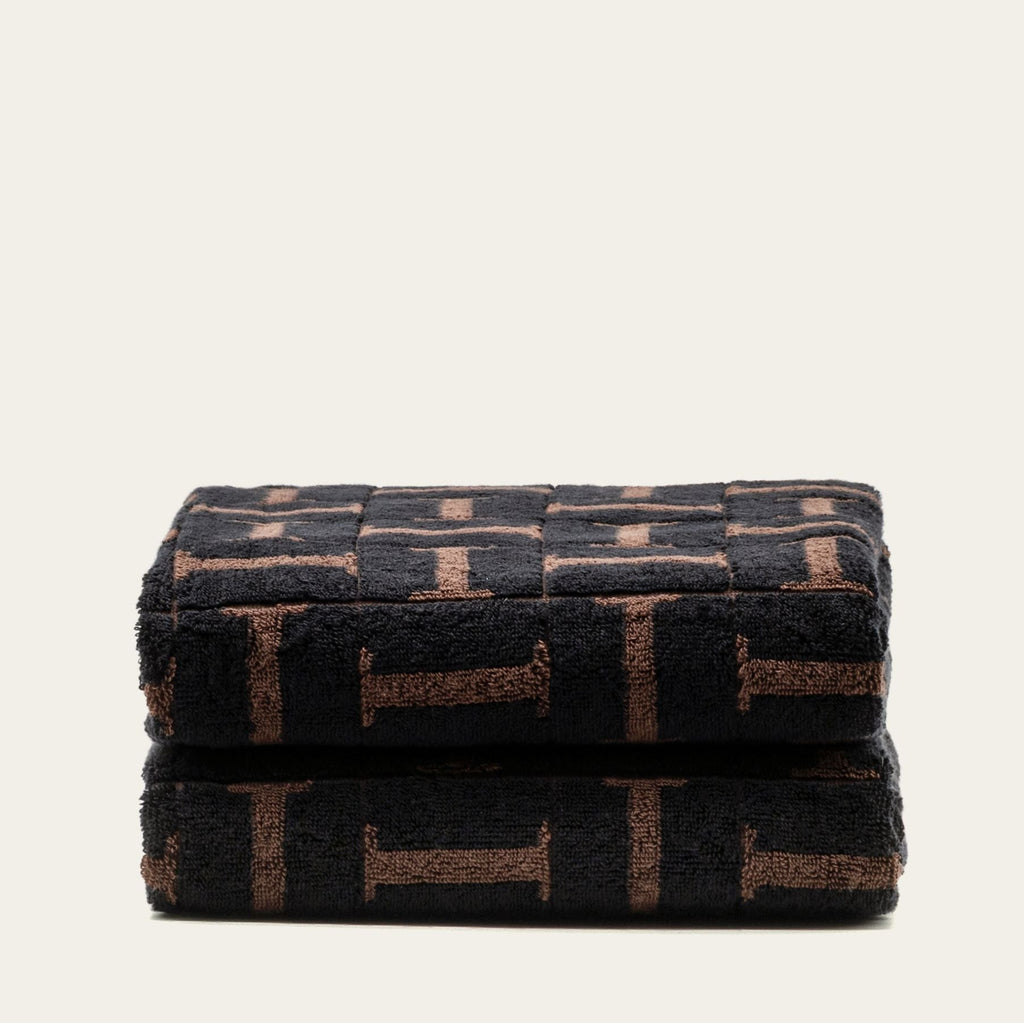 Folded terry cotton towels, tobacco and black geometric pattern, stacked neatly