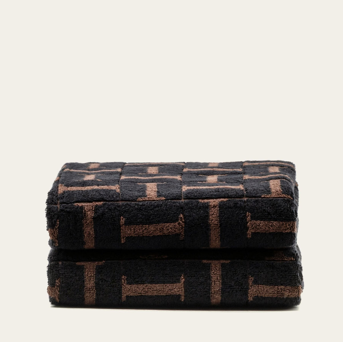Folded terry cotton towels, tobacco and black geometric pattern, stacked neatly