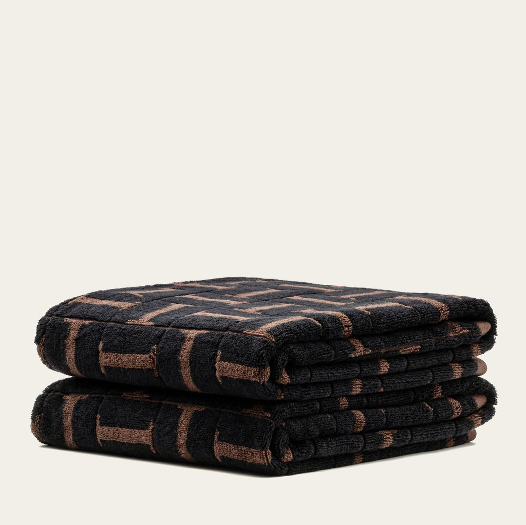Two stacked terry cotton towels with tobacco and black geometric pattern, folded over