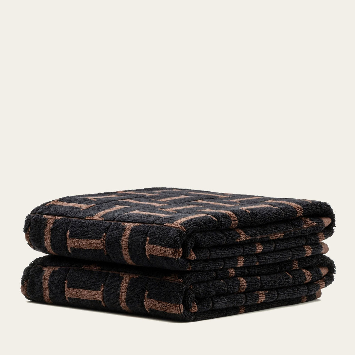 Two stacked terry cotton towels with tobacco and black geometric pattern, folded over