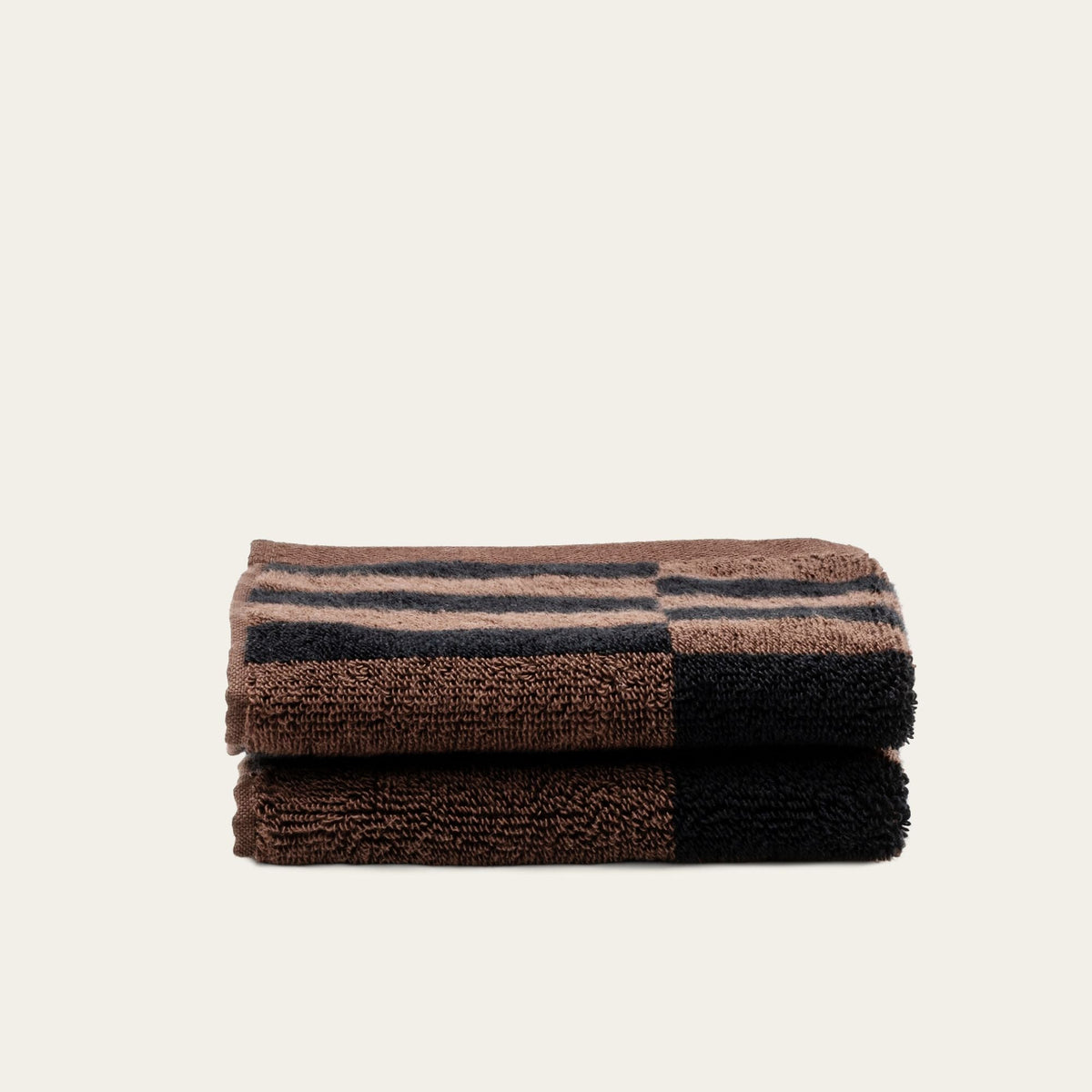 Folded striped cotton towels in tobacco brown and black, compact stack