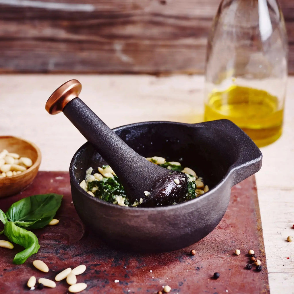 Black enameled mortar with pestle, filled with herbs and seasoning