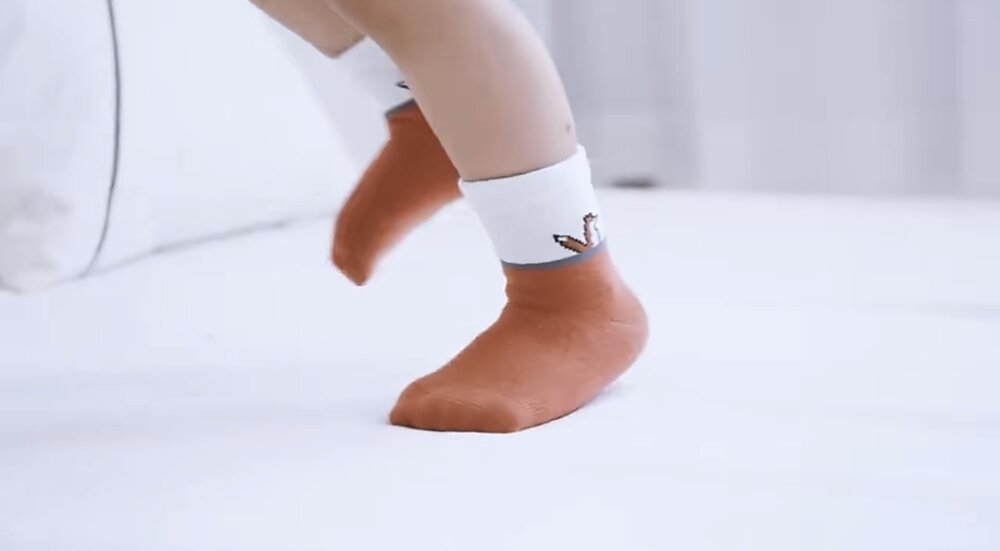 Toddler socks on a child’s foot: white crew with small fox logo at cuff