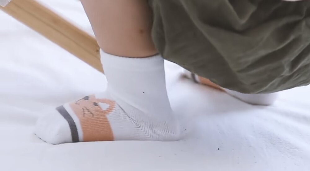 Kids' sock close-up: white with orange cat graphic and dark cuff stripes
