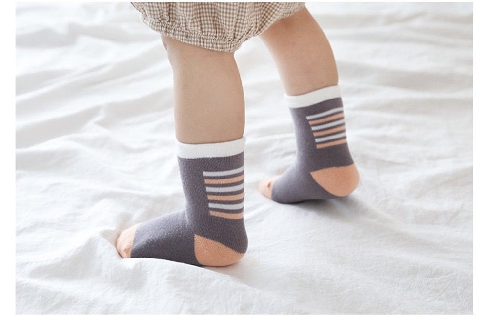 Kids' socks on legs: dark gray with peach toes and striped cuffs