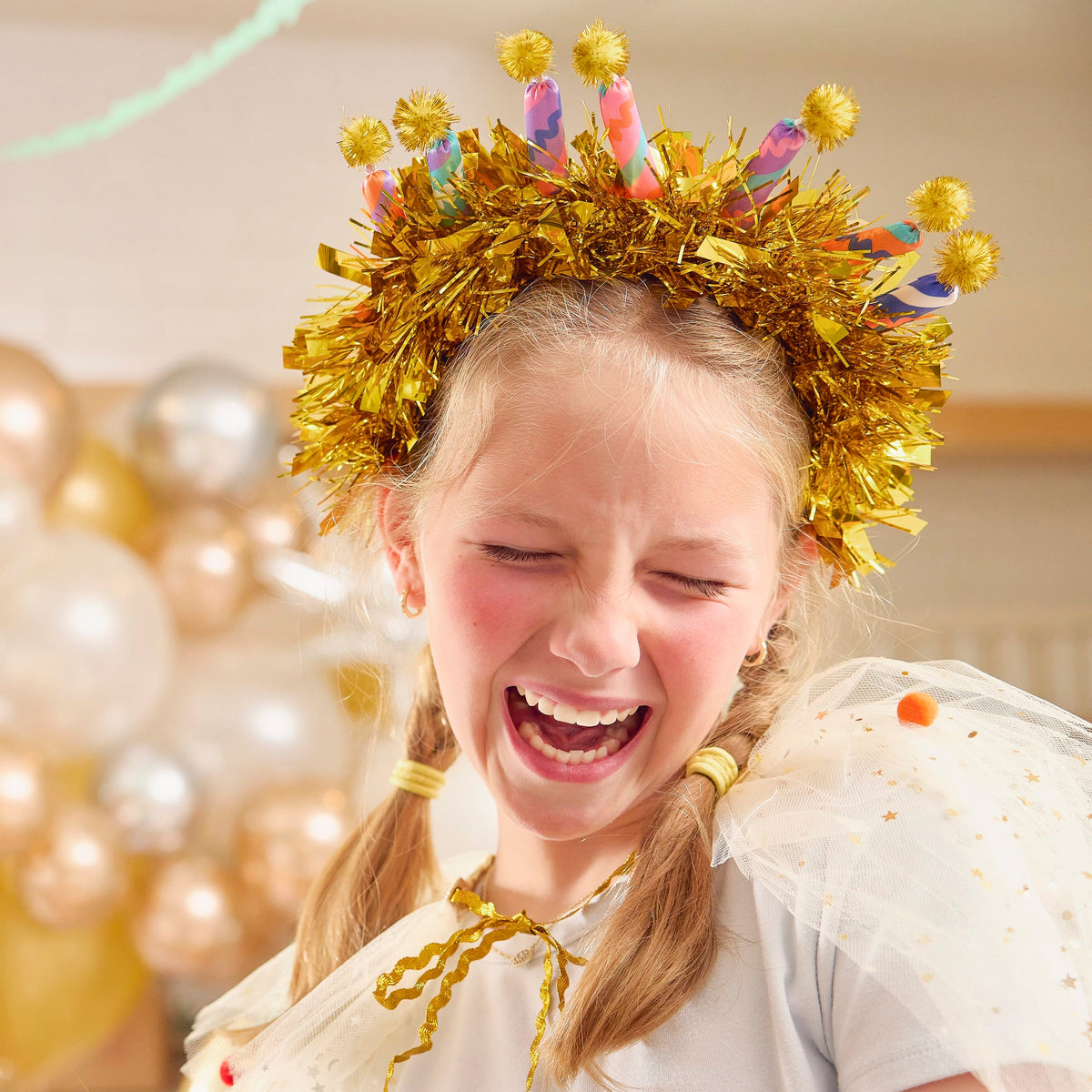 Gold tinsel headband with multicolor candle toppers and yellow pom-poms on top