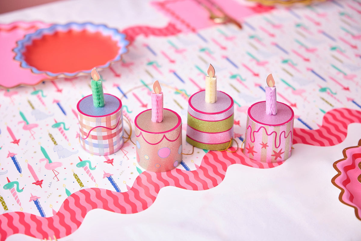 Mini birthday cake party hat set on table, four mini cylindrical hats with candle flames