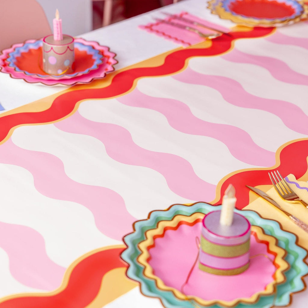 Pink cake party hat with candle on colorful birthday party table