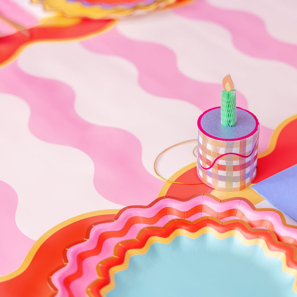 Mini birthday cake party hat on table, checkered mini cylinder with candle flame and cord