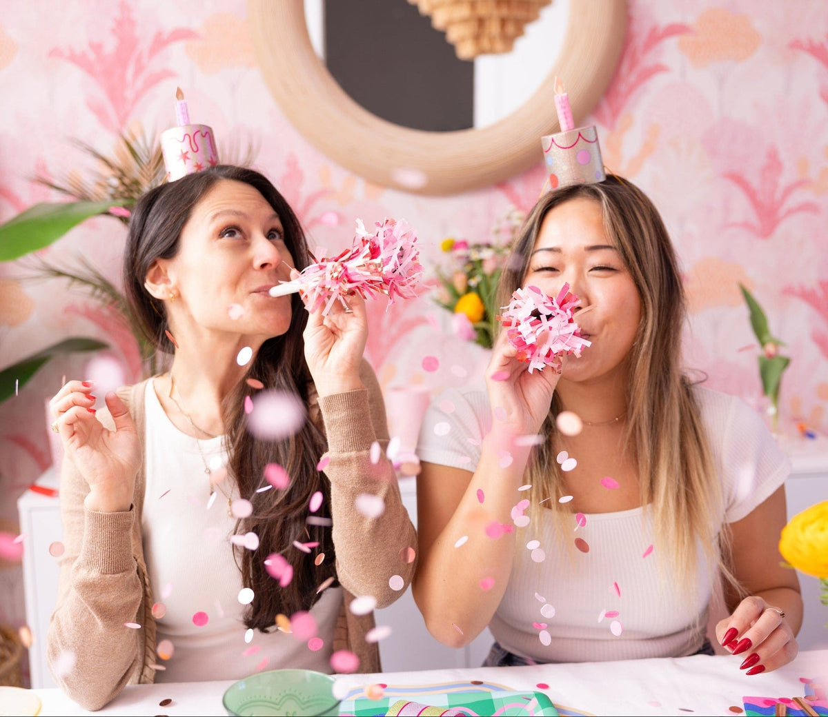 Mini birthday cake party hats on two people, pink candle toppers with glittery pom streamers