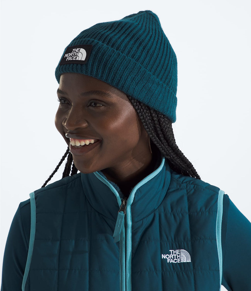Men’s TNF logo box beanie in teal-blue knit, worn with long hair braids