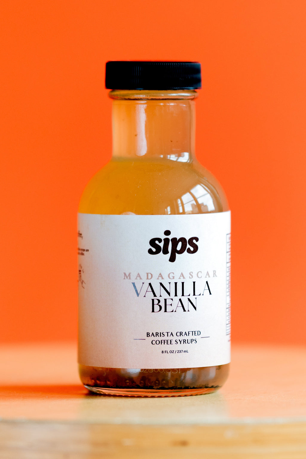Amber vanilla bean coffee syrup bottle with Sips label and black cap.