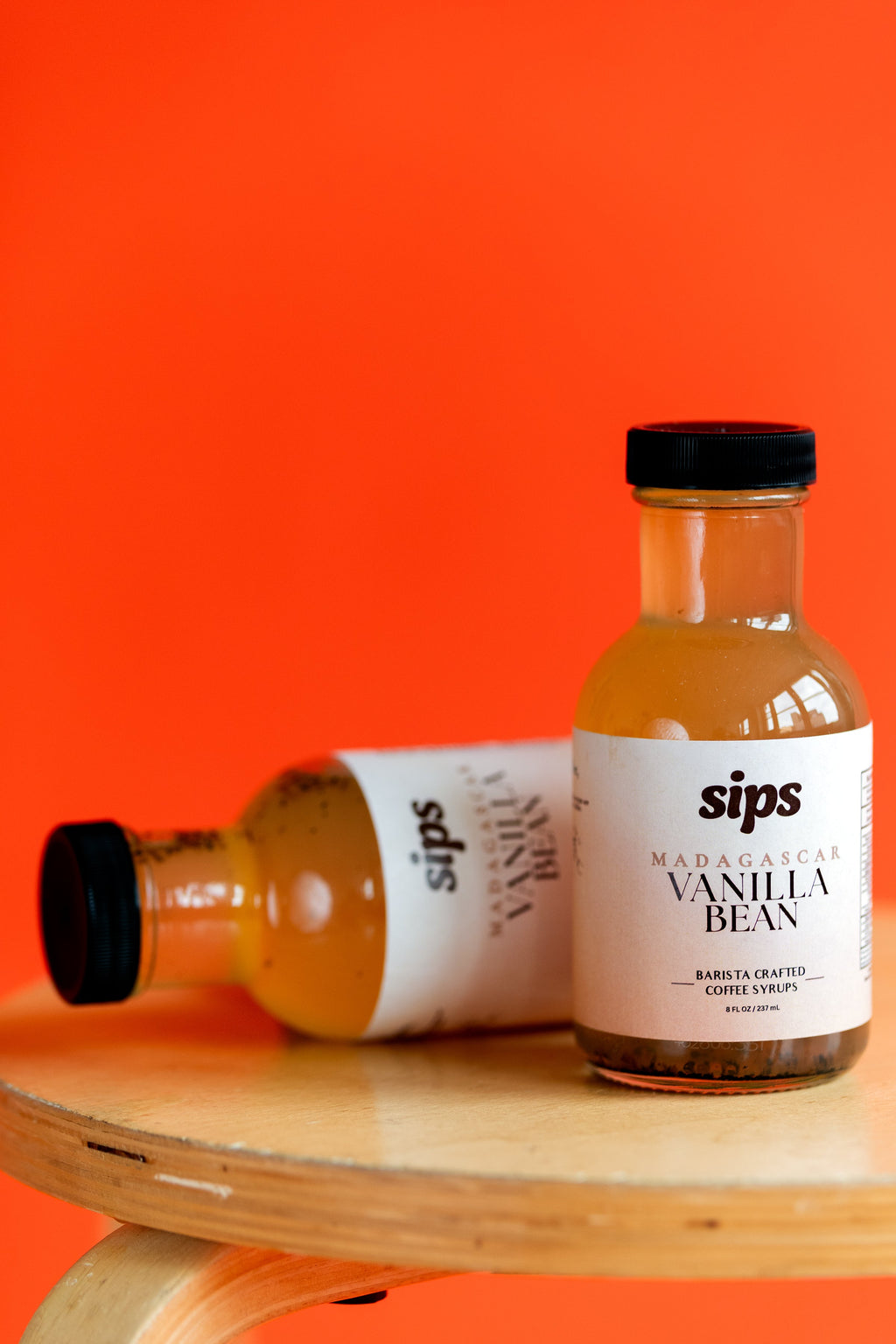 Vanilla bean coffee syrup bottle with Sips label, amber glass and black cap.
