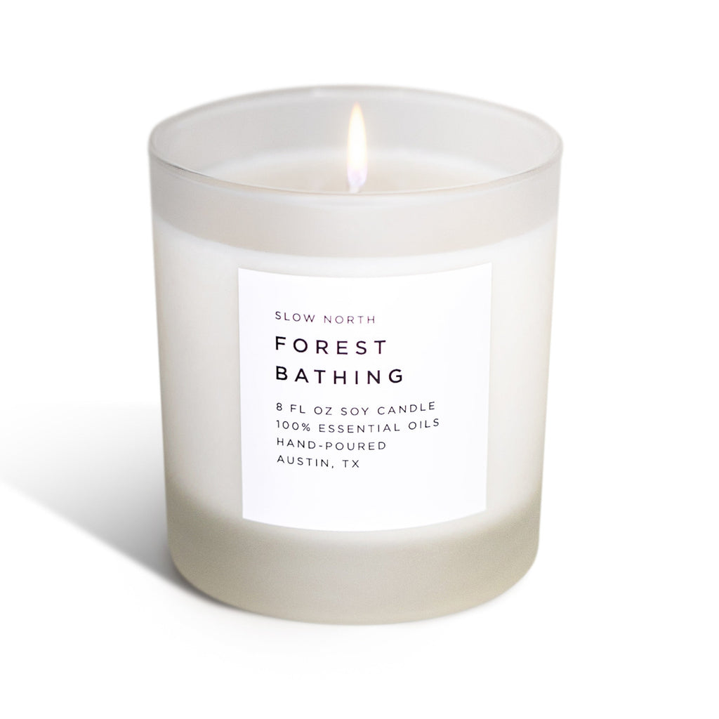 Soy candle in frosted jar with lit wick and front label