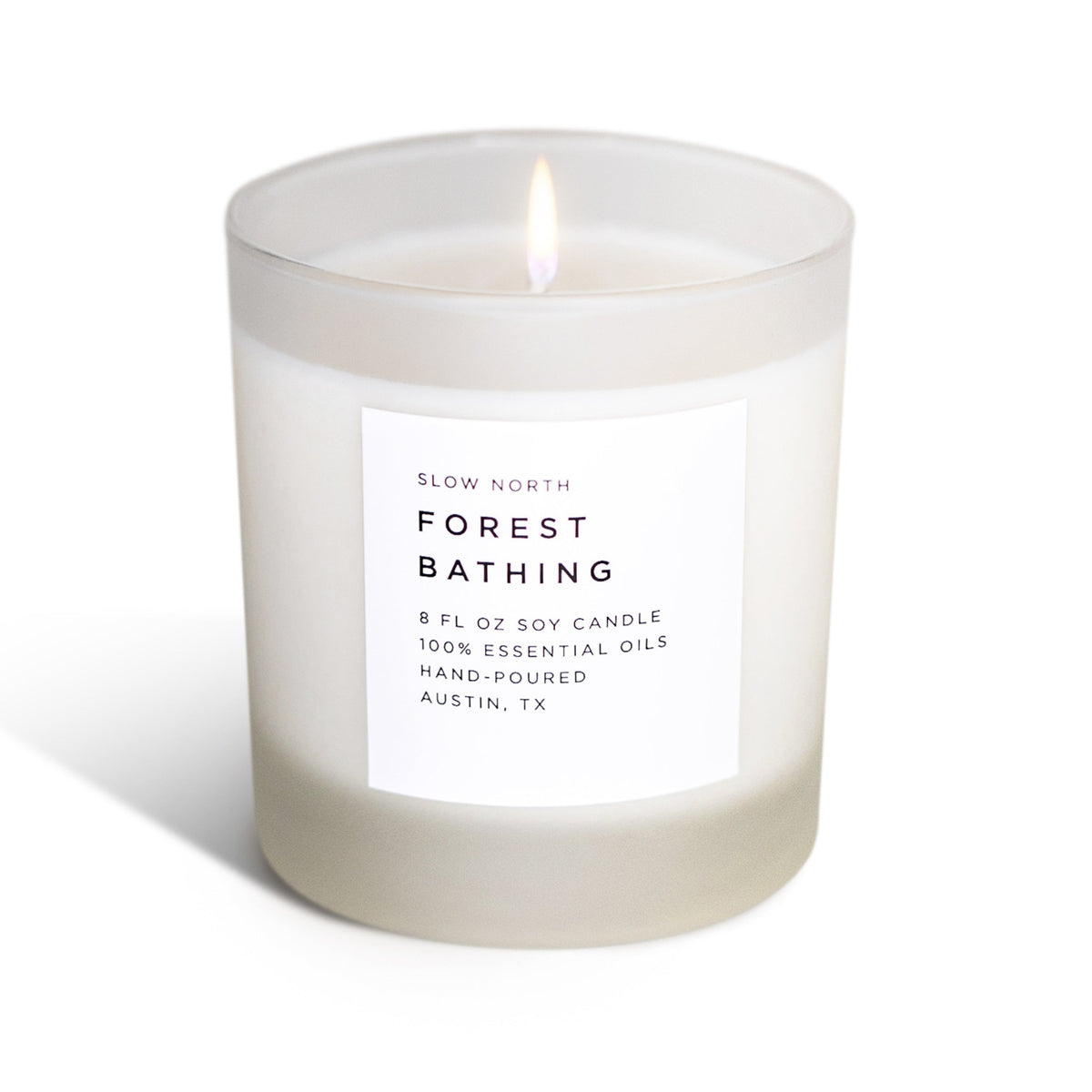 Soy candle in frosted jar with lit wick and front label