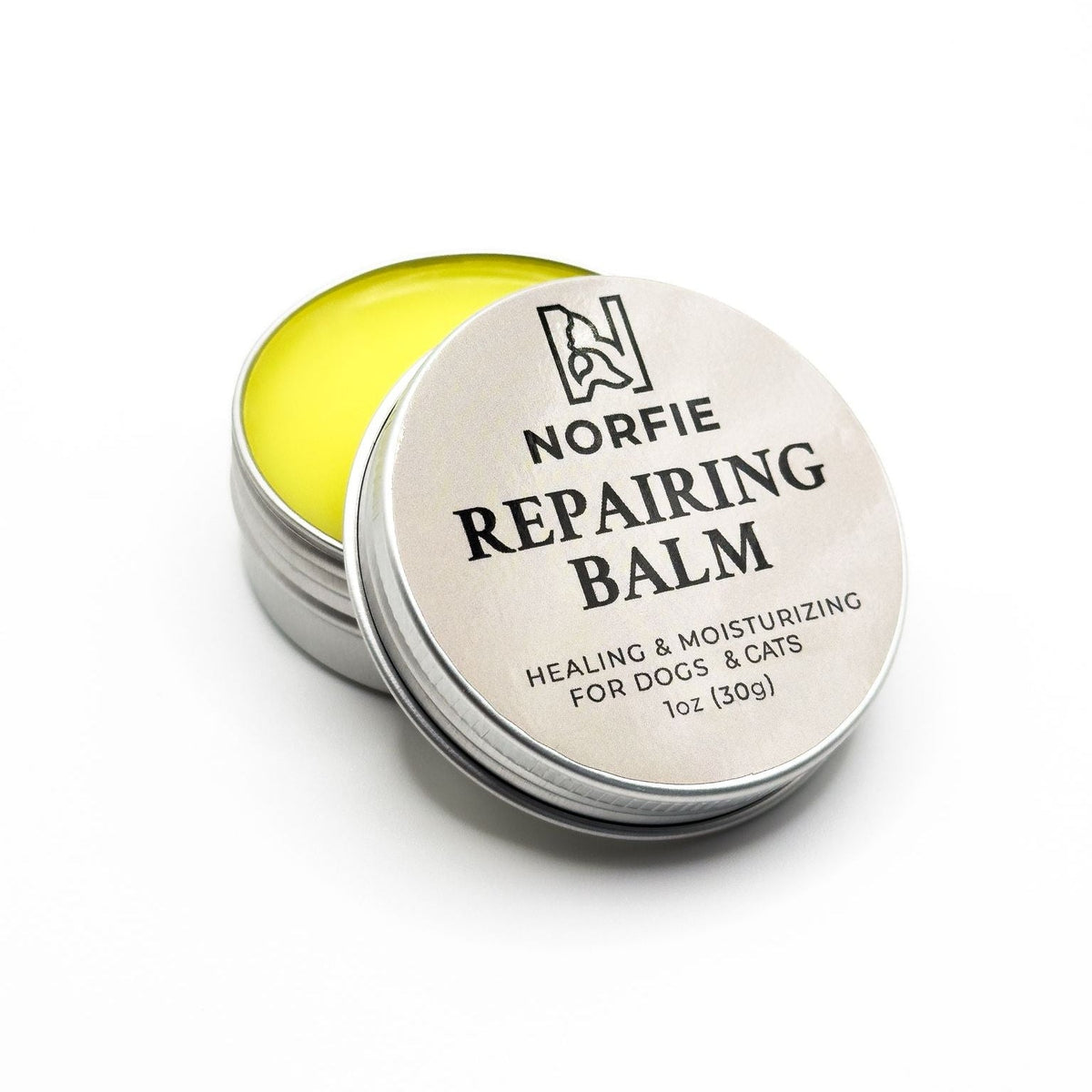 Pet repairing balm tin, silver lid open with yellow balm inside