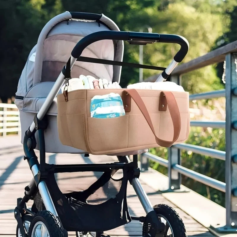 Grey felt stroller side storage bag with brown PU handles attached to pushchair