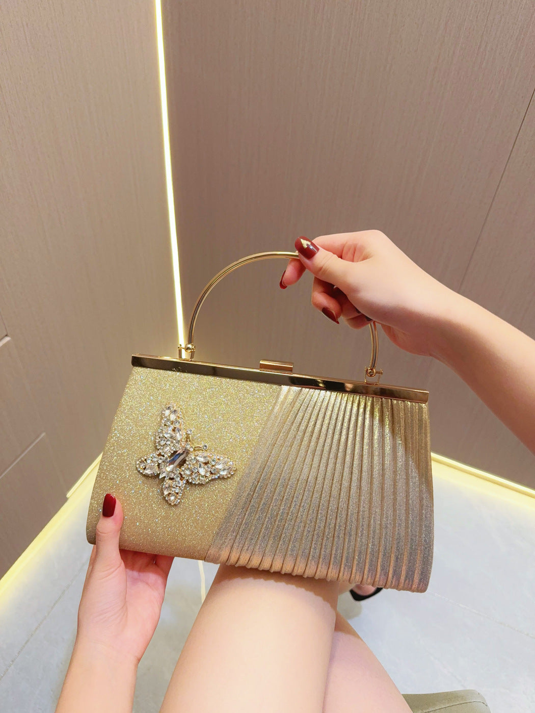 Gold pleated evening clutch with top handle and jeweled flower front