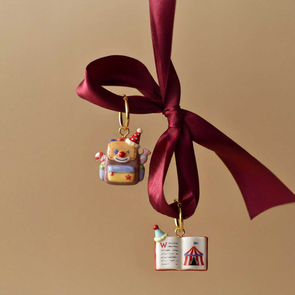 Miniature school-supply keychain charm hanging from a burgundy ribbon