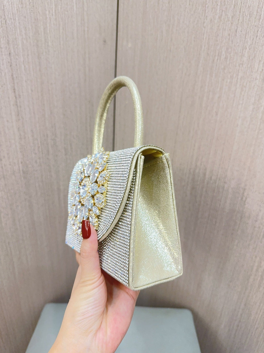 Gold jeweled mini clutch with rhinestone top handle and side flap profile