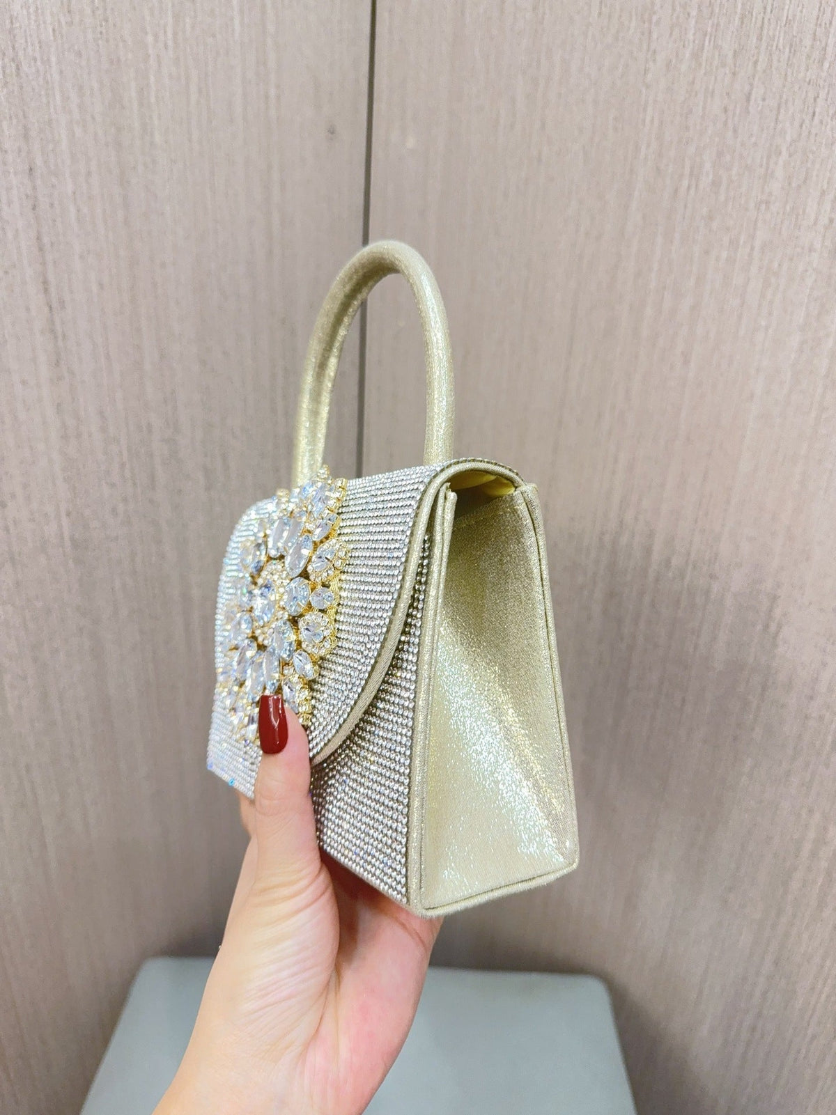 Gold jeweled mini clutch with rhinestone top handle and side flap profile