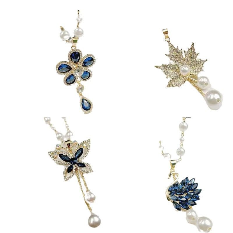 Assorted long pearl necklaces: blue flower, gold star, and blue leaf charms