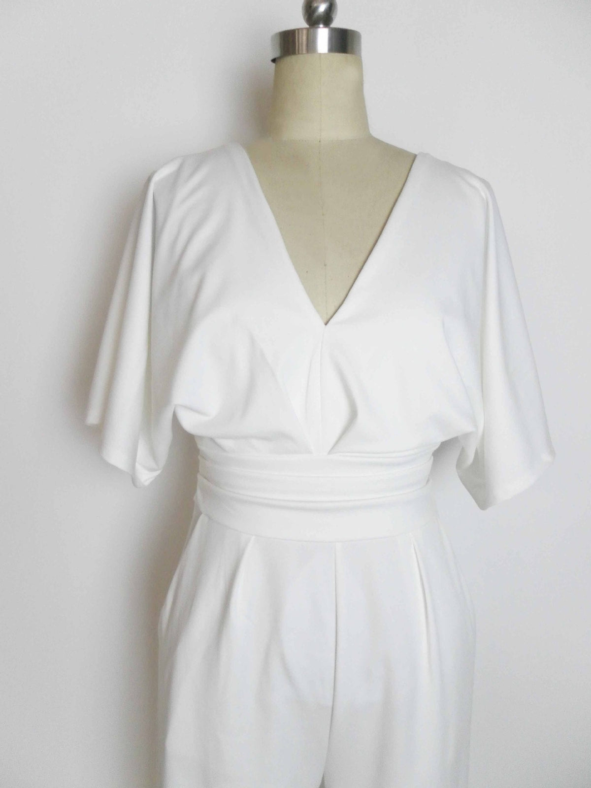 White deep V-neck jumpsuit with ruching at waist and wide flutter sleeves