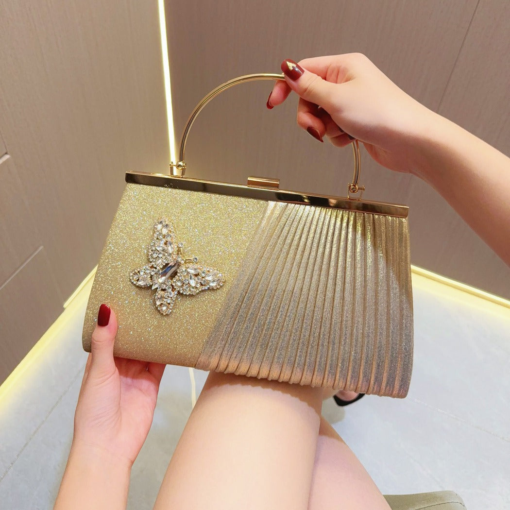 Gold pleated clutch with jeweled floral embellishment and curved handle
