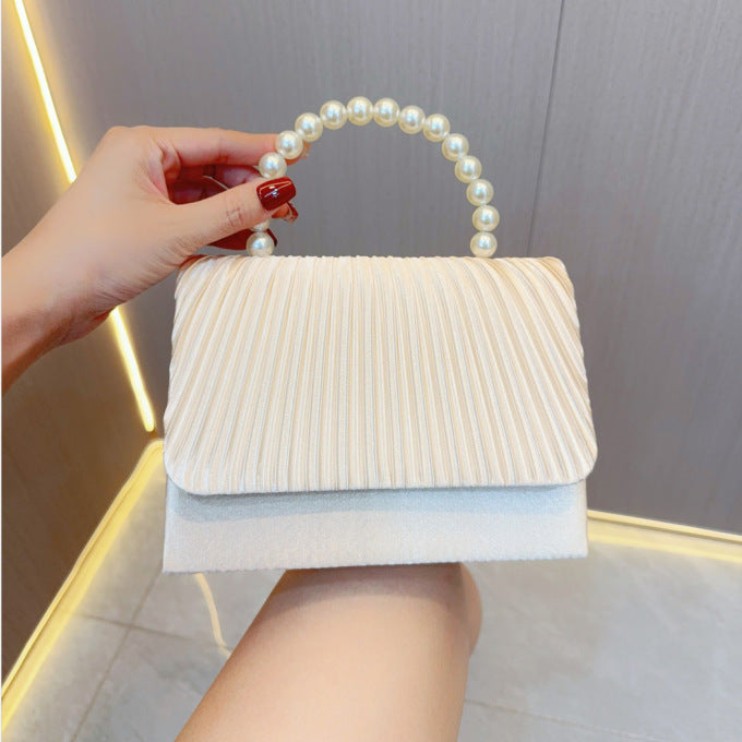 White pleated evening clutch bag with faux pearl handle and top flap