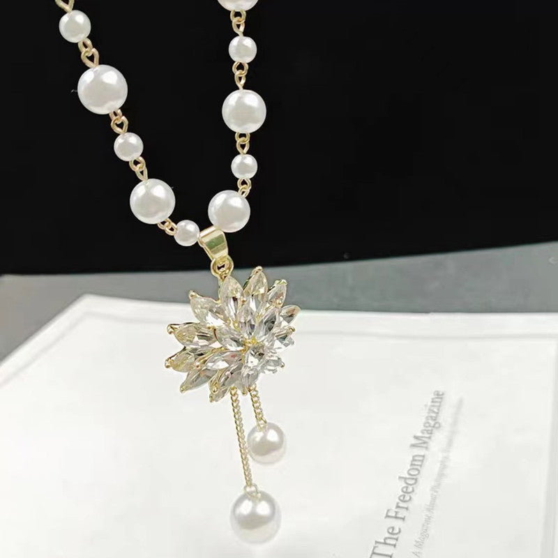 Long pearl necklace with crystal starburst pendant, gold stem, and pearl tassel