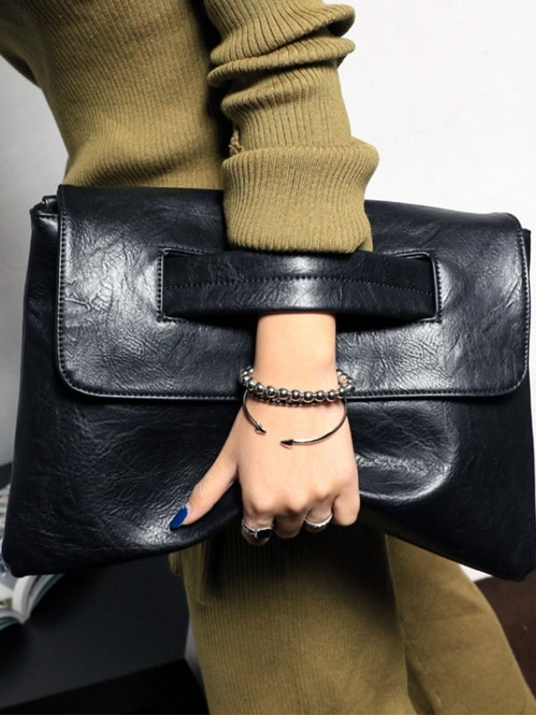 Black leather envelope clutch purse held by the front flap and wide top opening