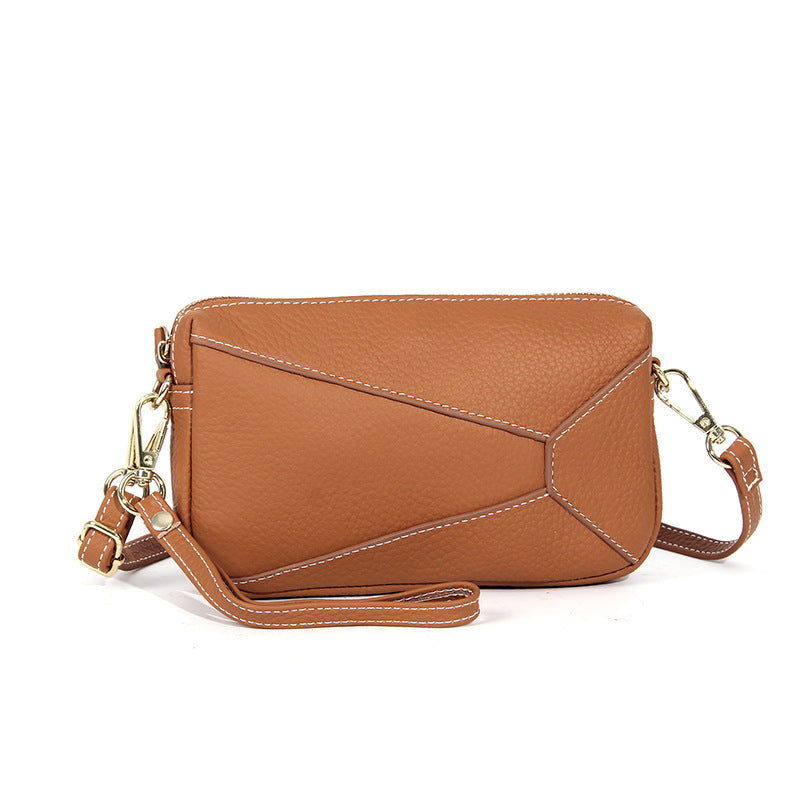 Tan leather wristlet bag with front flap and adjustable crossbody strap